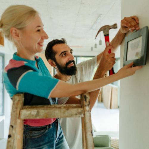 Man and woman working together to hang a photo on a wall.