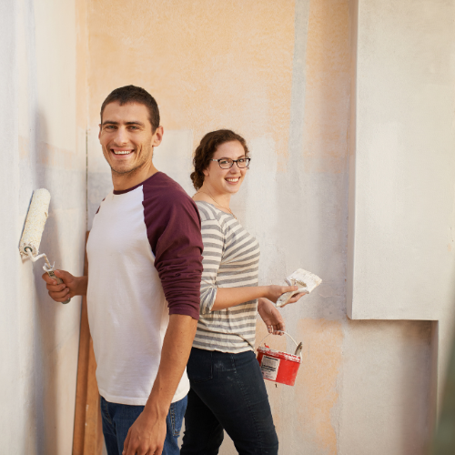 Man and woman smiling at the camera as they prepare to tackle a DIY home upgrade.