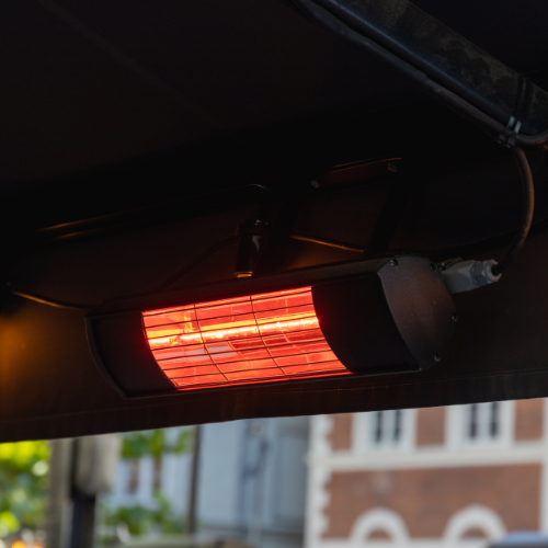 Wall-mounted electric patio heater glowing red.